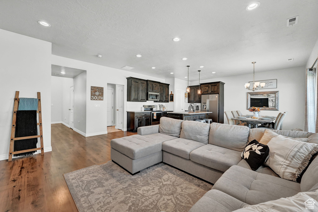 Living room featuring sink, a notable chandelier, and light hardwood / wood-style flooring