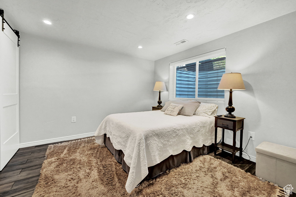 Bedroom featuring dark hardwood / wood-style flooring and a barn door