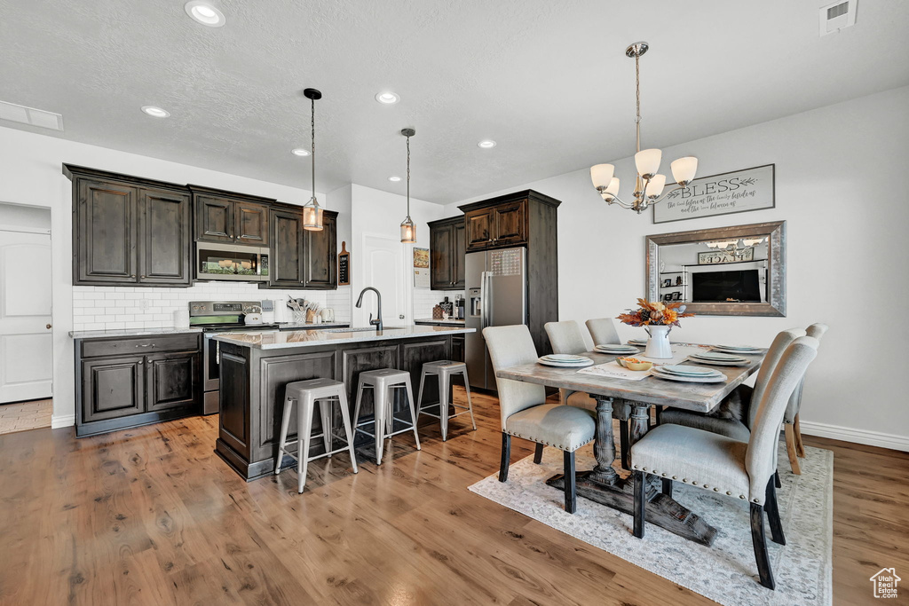 Dining room featuring wood-type flooring, an inviting chandelier, and sink