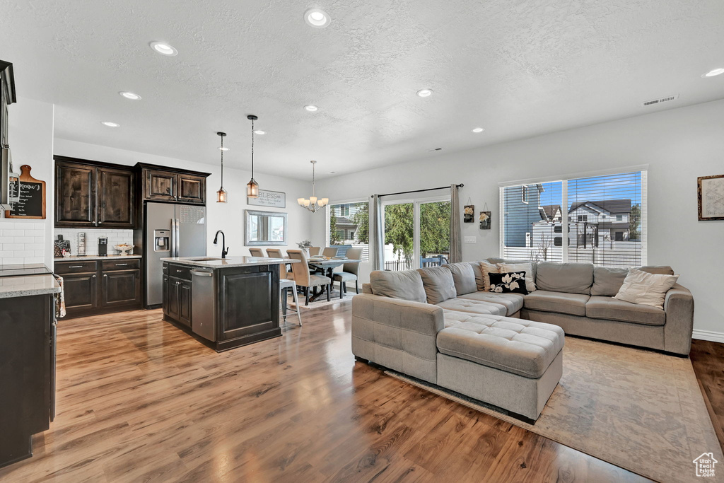 Living room featuring light wood-type flooring, a textured ceiling, a chandelier, and sink