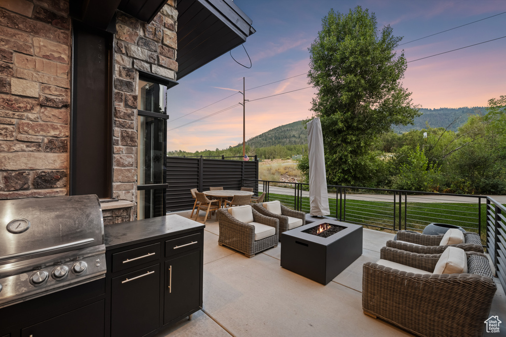 Patio terrace at dusk with a grill, an outdoor living space with a fire pit, and a mountain view