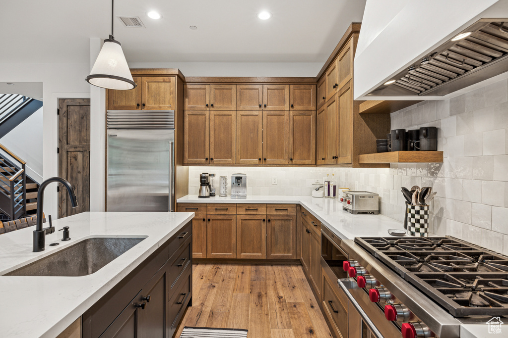 Kitchen with high end appliances, pendant lighting, tasteful backsplash, and sink