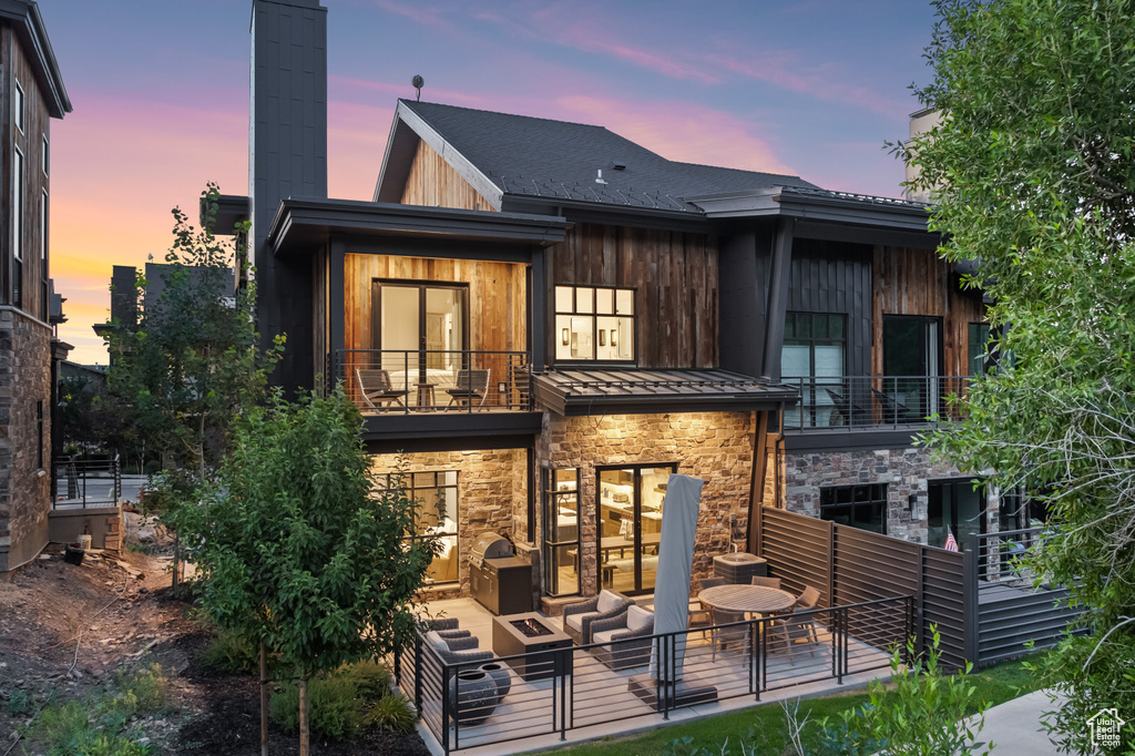 Back house at dusk with an outdoor hangout area and a balcony