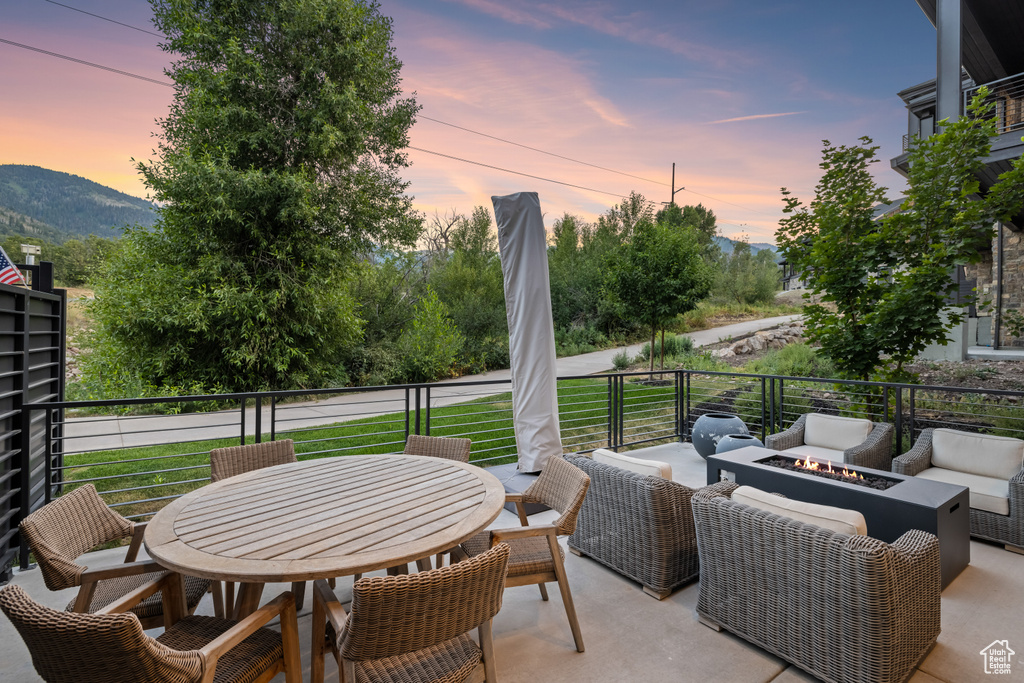 Patio terrace at dusk featuring a balcony, a mountain view, and outdoor lounge area