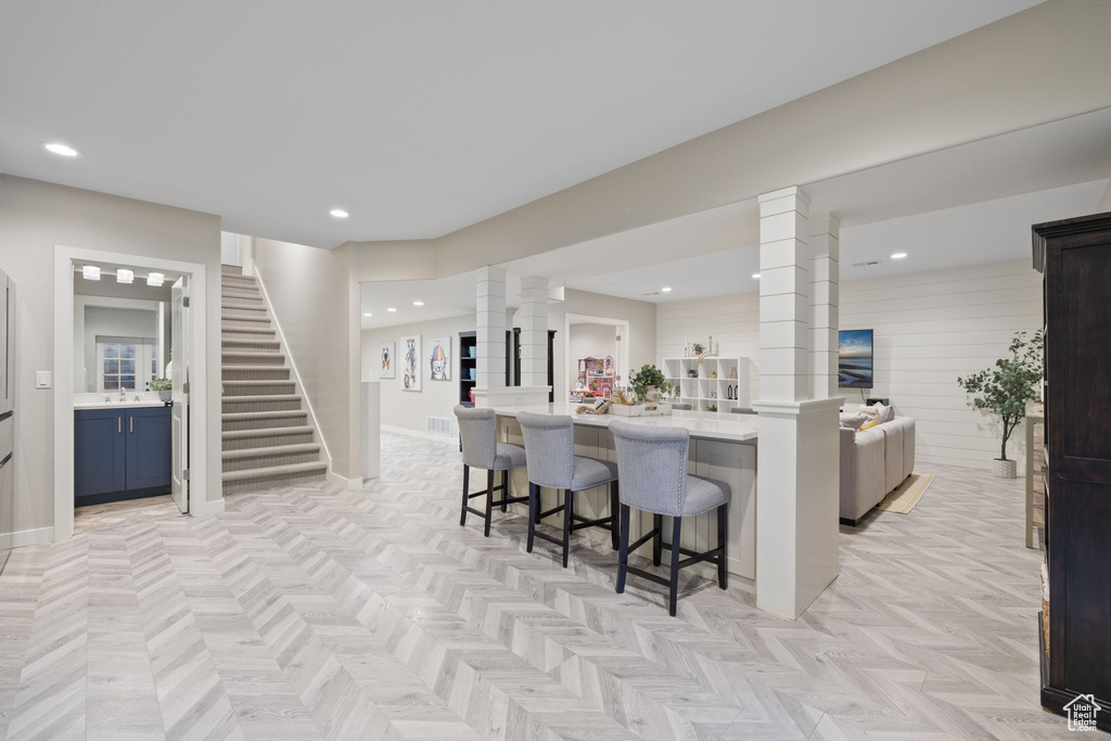 Kitchen with blue cabinets, decorative columns, light parquet floors, and a breakfast bar