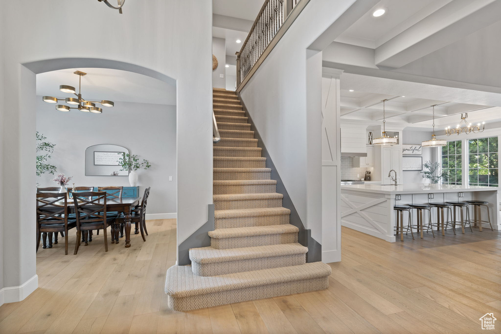 Stairway featuring an inviting chandelier, hardwood / wood-style flooring, beam ceiling, and sink