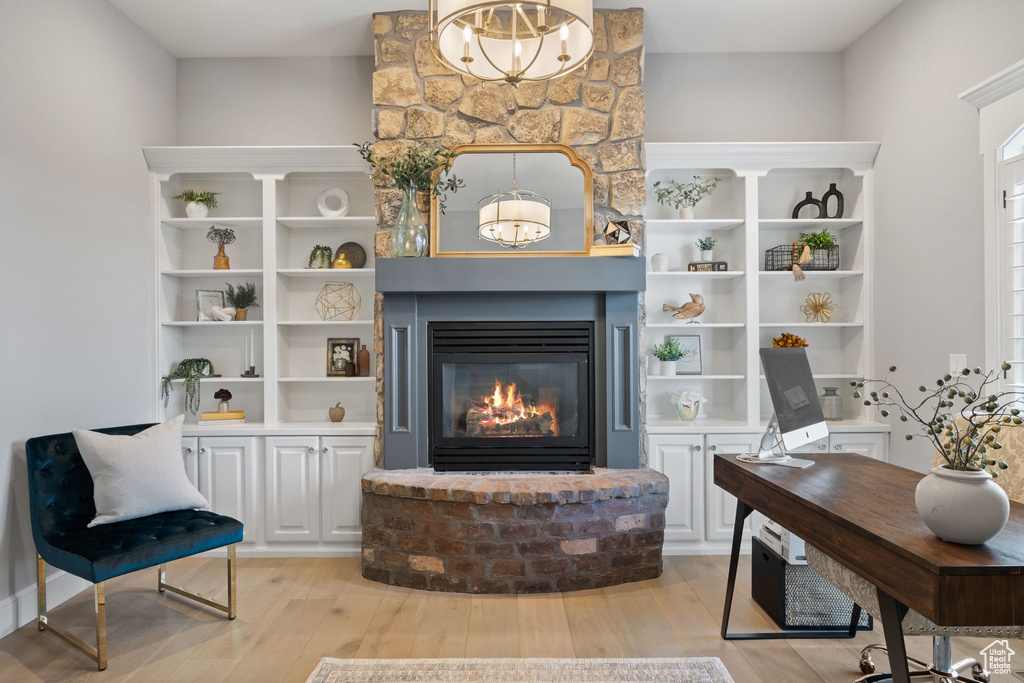 Living room with light hardwood / wood-style floors, a large fireplace, and a notable chandelier