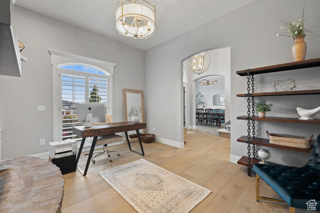 Office area with an inviting chandelier and light hardwood / wood-style flooring