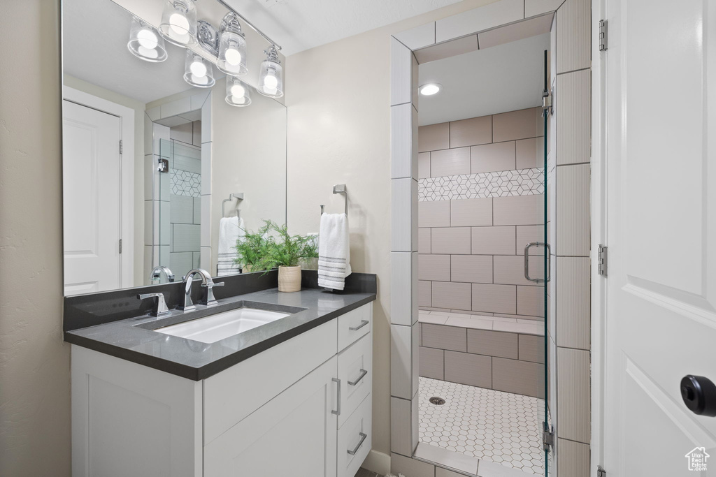 Bathroom featuring a shower with door and vanity