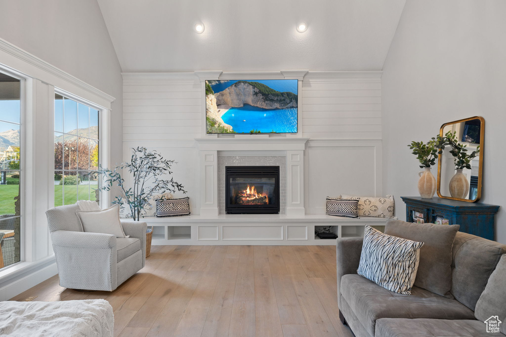 Living room featuring high vaulted ceiling, light wood-type flooring, and wooden walls