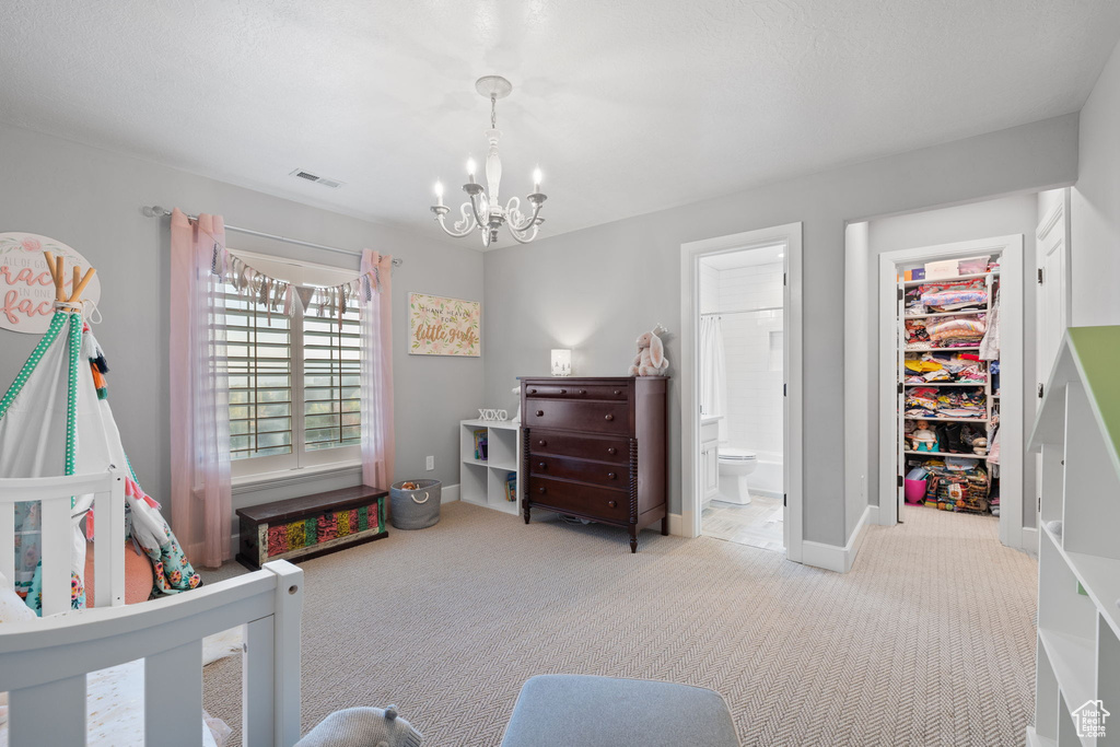 Carpeted bedroom with connected bathroom and a chandelier