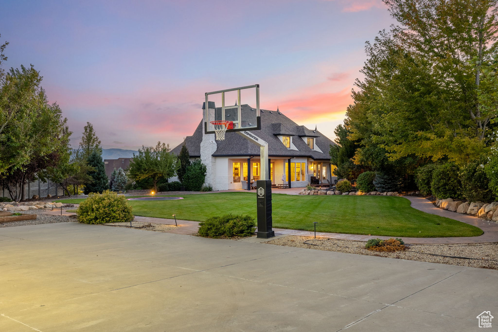 Exterior space with basketball hoop and a yard