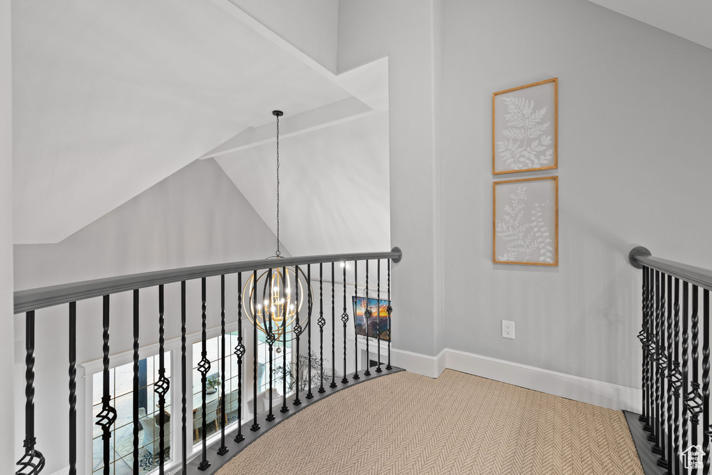 Hallway featuring carpet floors, lofted ceiling, and a chandelier