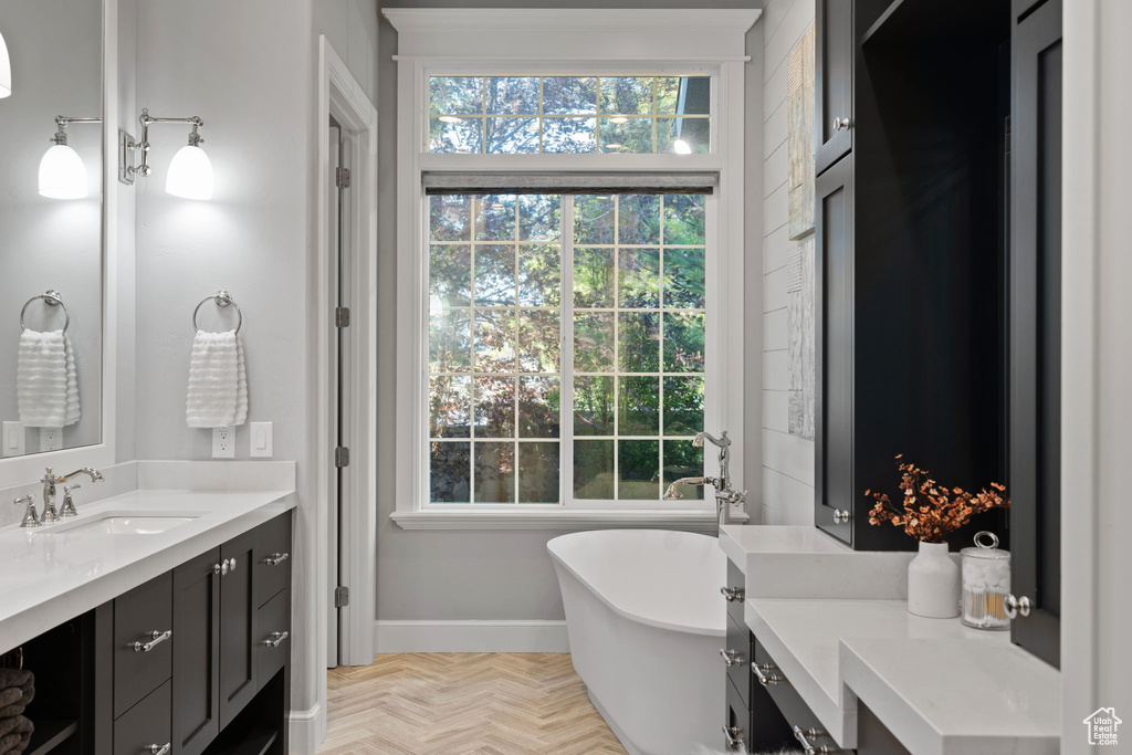 Bathroom with a bath, parquet floors, and vanity