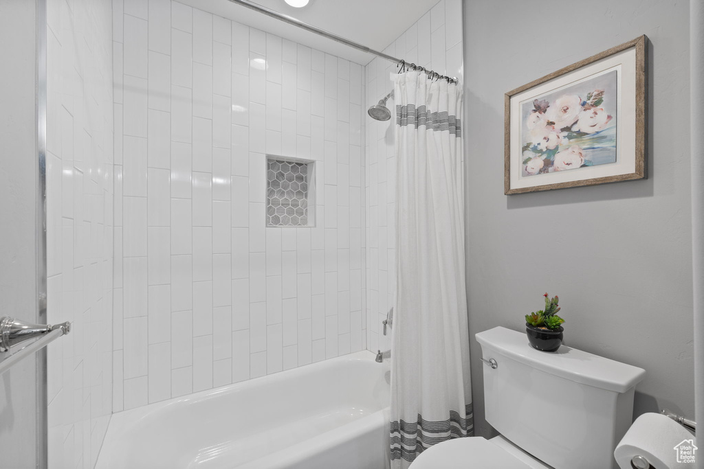 Bathroom featuring toilet and shower / tub combo with curtain