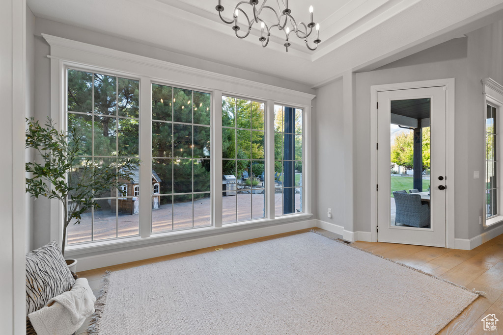 Doorway with an inviting chandelier, hardwood / wood-style flooring, and a raised ceiling