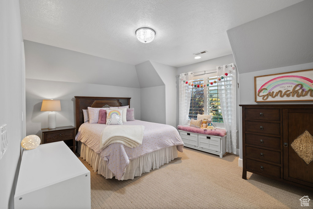 Carpeted bedroom featuring a textured ceiling and vaulted ceiling