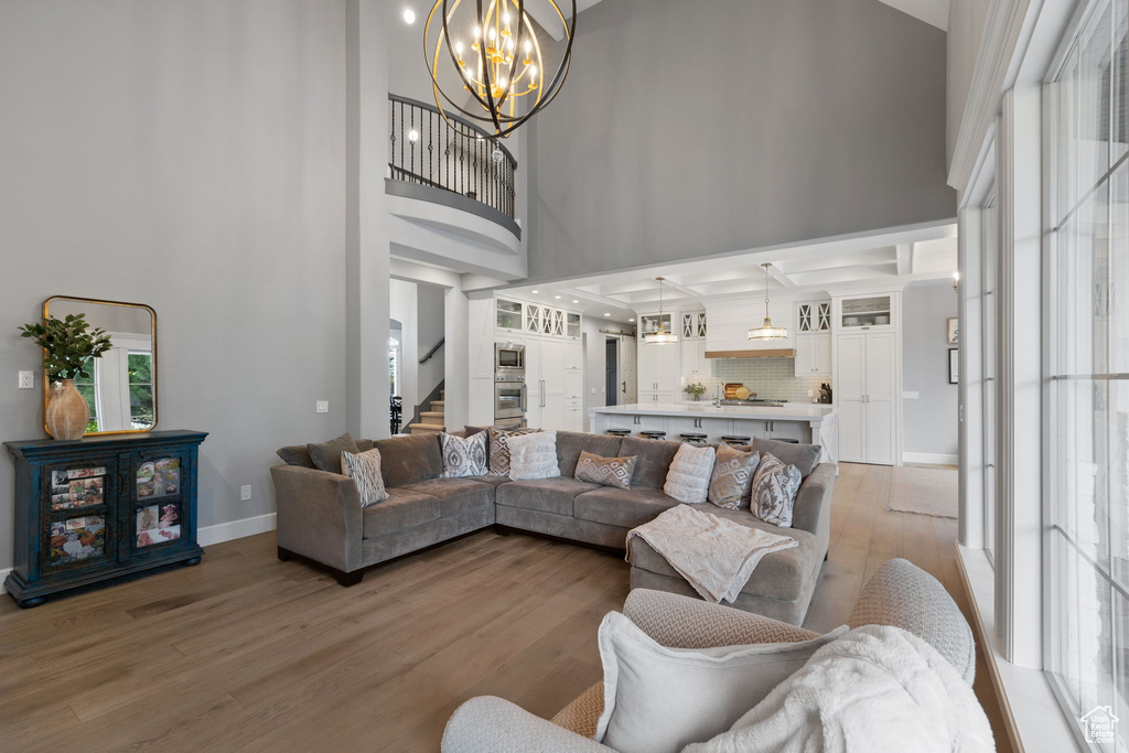 Living room featuring a notable chandelier, a towering ceiling, and light hardwood / wood-style floors