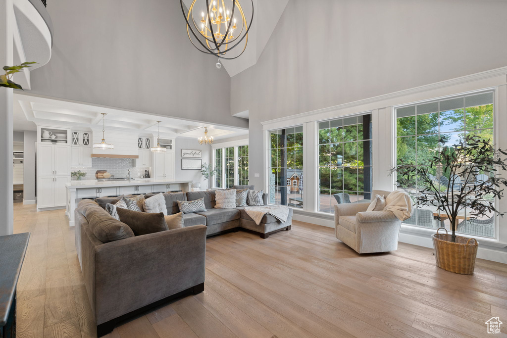 Living room featuring a notable chandelier, a high ceiling, and light hardwood / wood-style floors