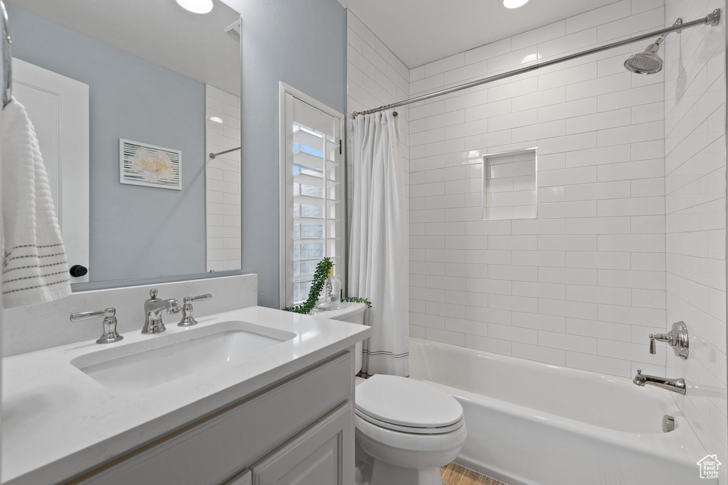 Full bathroom featuring shower / bath combination with curtain, vanity, and toilet