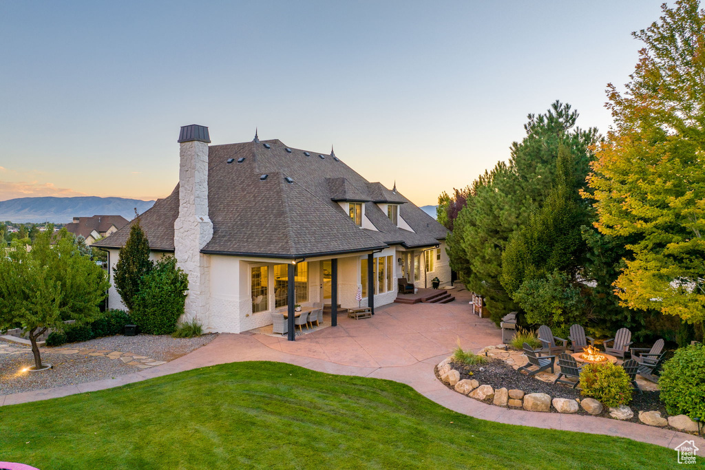 Back house at dusk with a yard, a patio area, and an outdoor fire pit