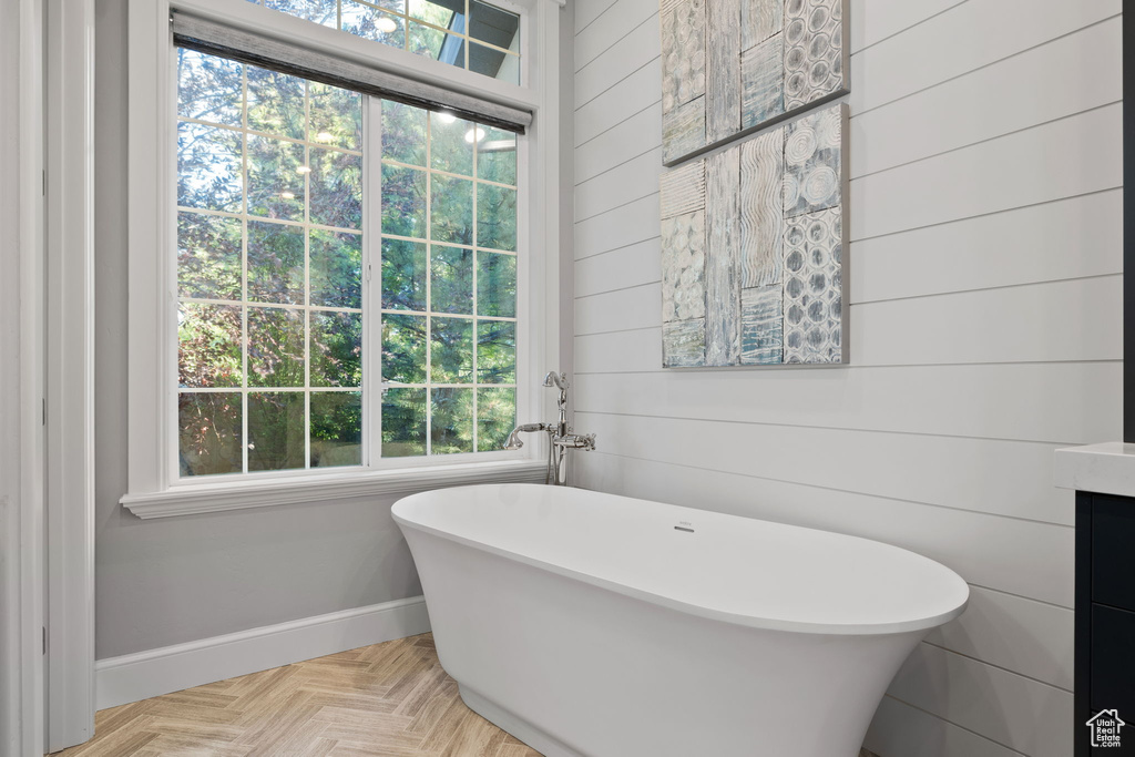 Bathroom with a healthy amount of sunlight, wood walls, and a tub