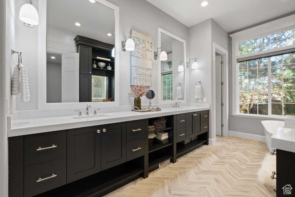 Bathroom featuring a tub to relax in, vanity, and parquet flooring