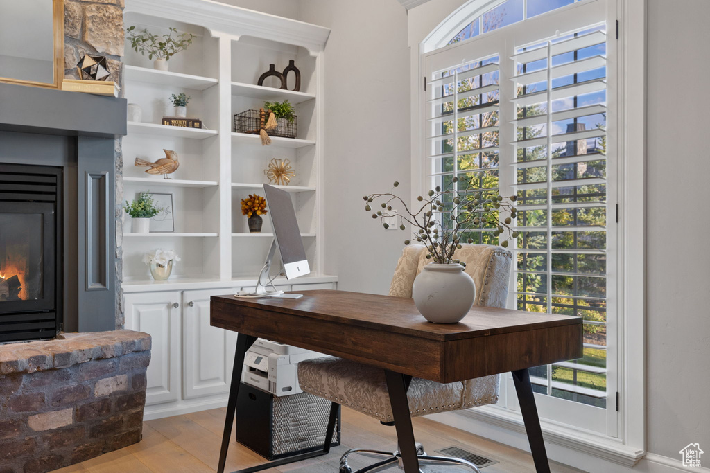 Office with a stone fireplace and light hardwood / wood-style flooring