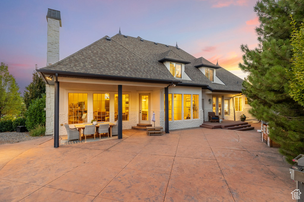 Back house at dusk featuring a patio area