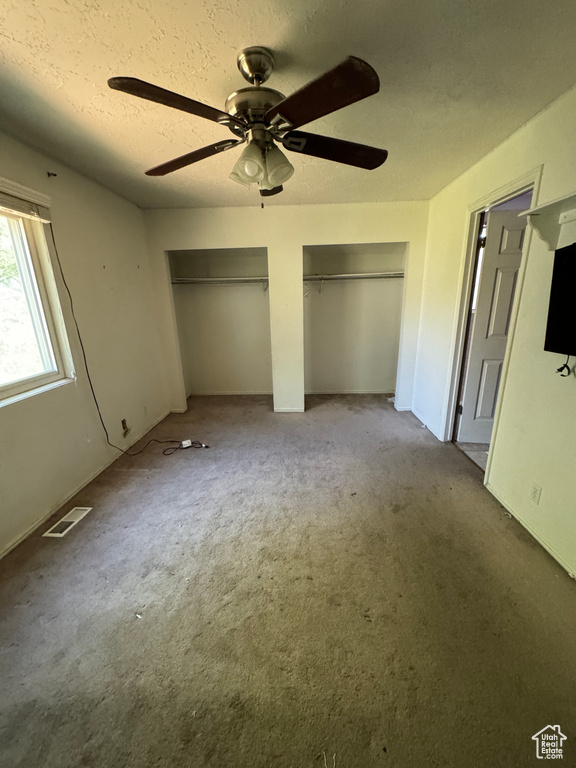 Unfurnished bedroom with two closets, carpet flooring, and ceiling fan