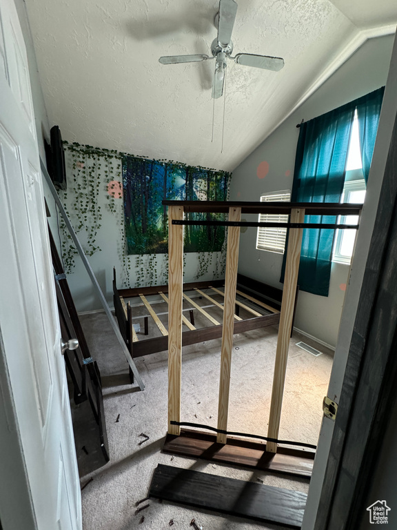 Bedroom with lofted ceiling, ceiling fan, and a textured ceiling