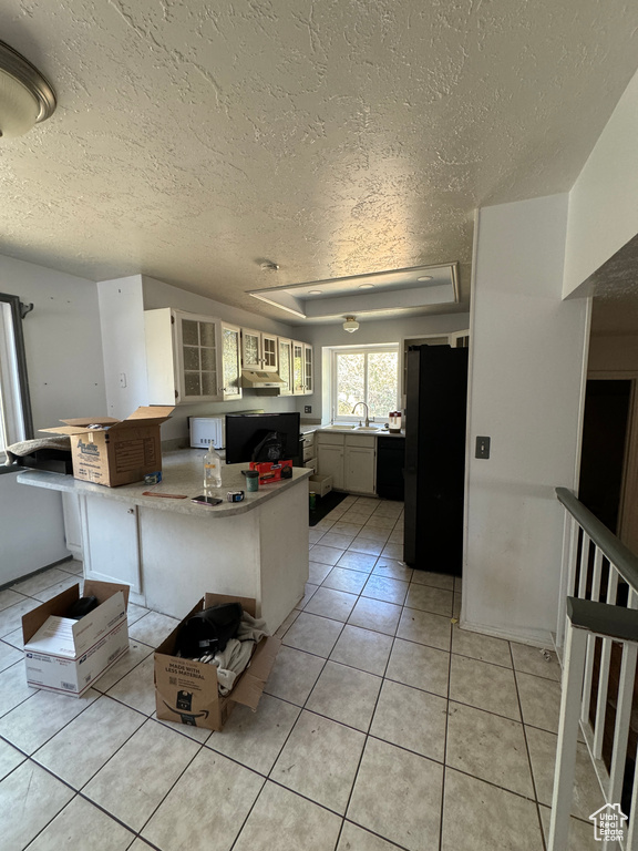 Kitchen featuring a textured ceiling, kitchen peninsula, sink, and light tile patterned floors