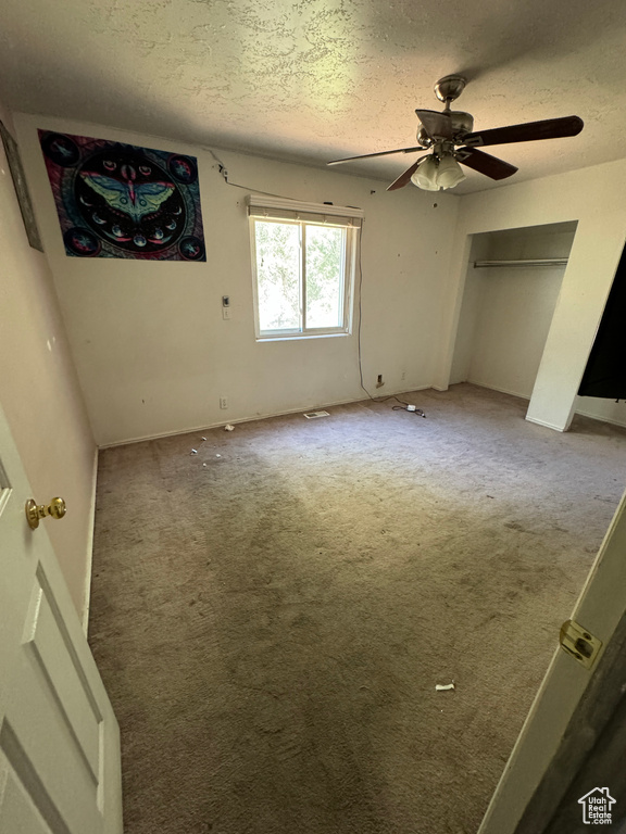 Unfurnished bedroom featuring carpet flooring, ceiling fan, and a textured ceiling