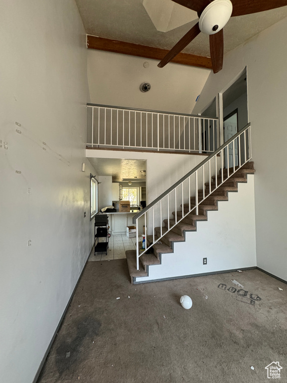 Staircase with ceiling fan and high vaulted ceiling