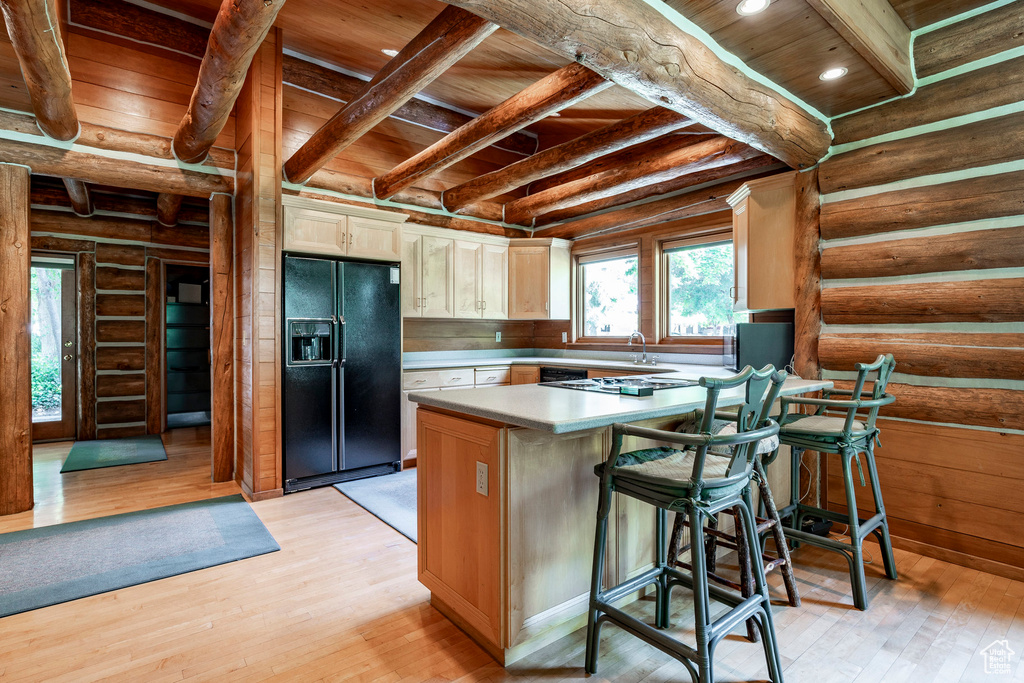 Kitchen with black fridge, wooden ceiling, log walls, and light hardwood / wood-style flooring