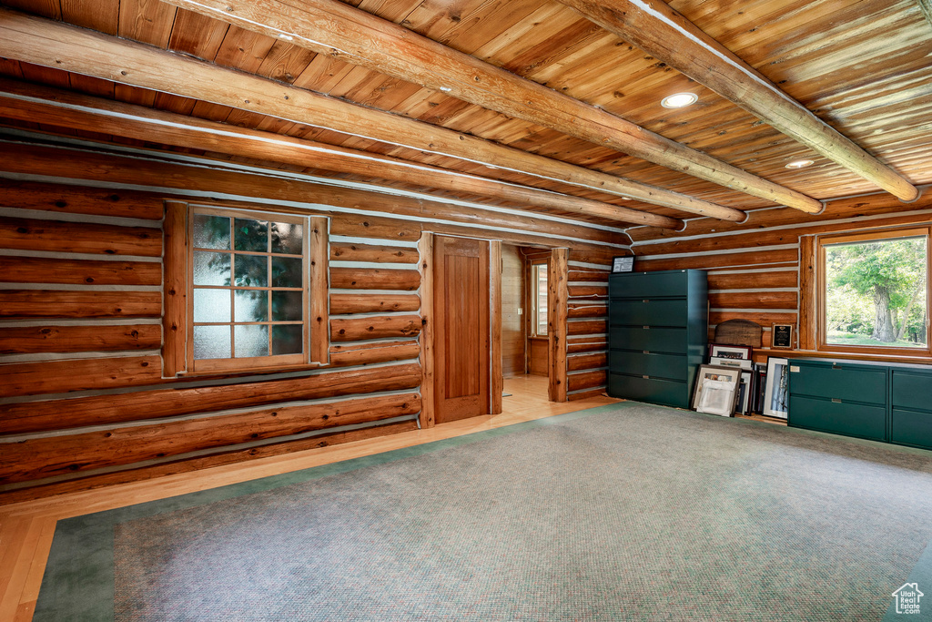 Unfurnished living room with hardwood / wood-style flooring, wooden ceiling, rustic walls, and beam ceiling