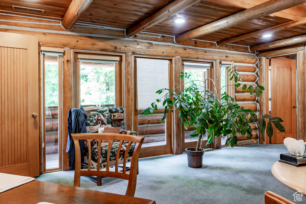 Carpeted dining area featuring wood ceiling, beam ceiling, and log walls