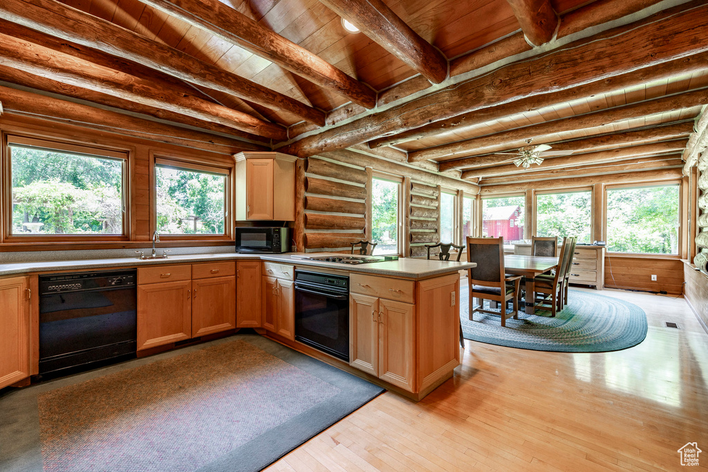 Kitchen featuring wooden ceiling, light hardwood / wood-style flooring, black appliances, rustic walls, and beam ceiling