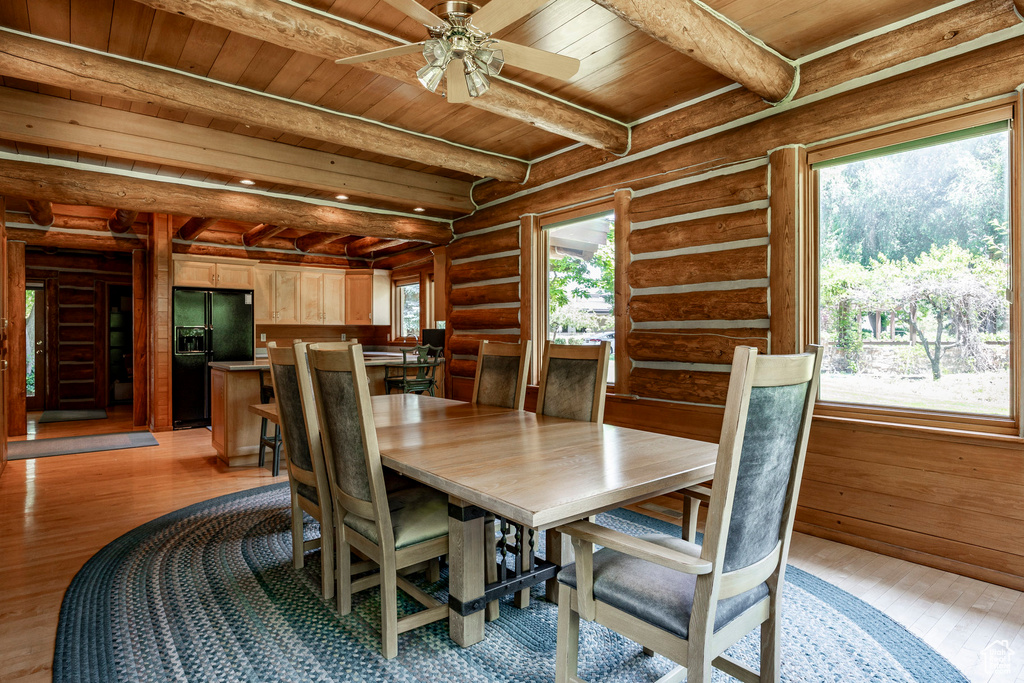 Dining space with light wood-type flooring, a wealth of natural light, wooden ceiling, and rustic walls