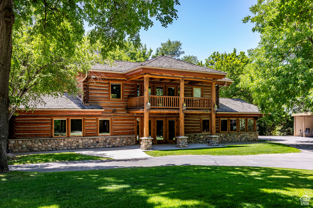 Log-style house with a balcony and a front yard