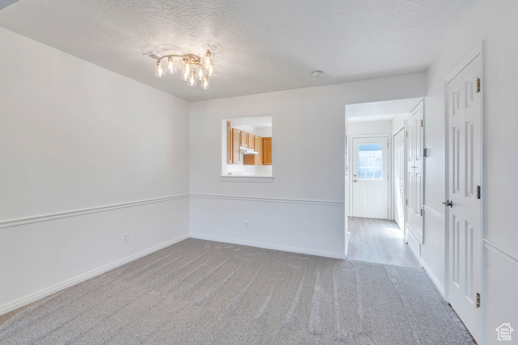 Spare room featuring light carpet and a textured ceiling