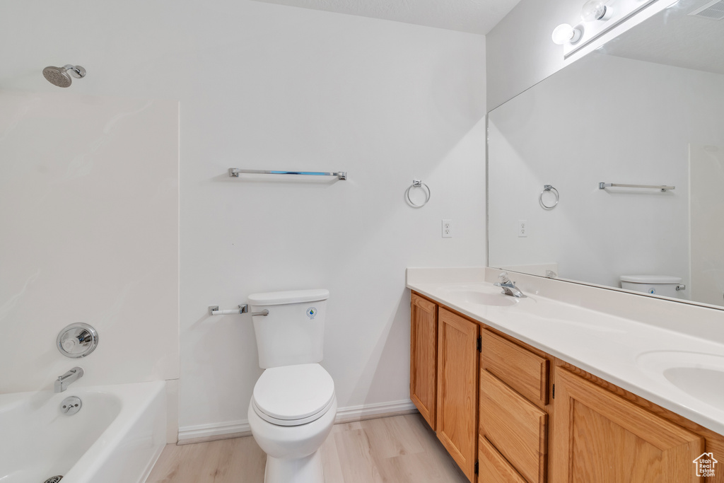 Full bathroom featuring vanity, toilet, wood-type flooring, and bathtub / shower combination