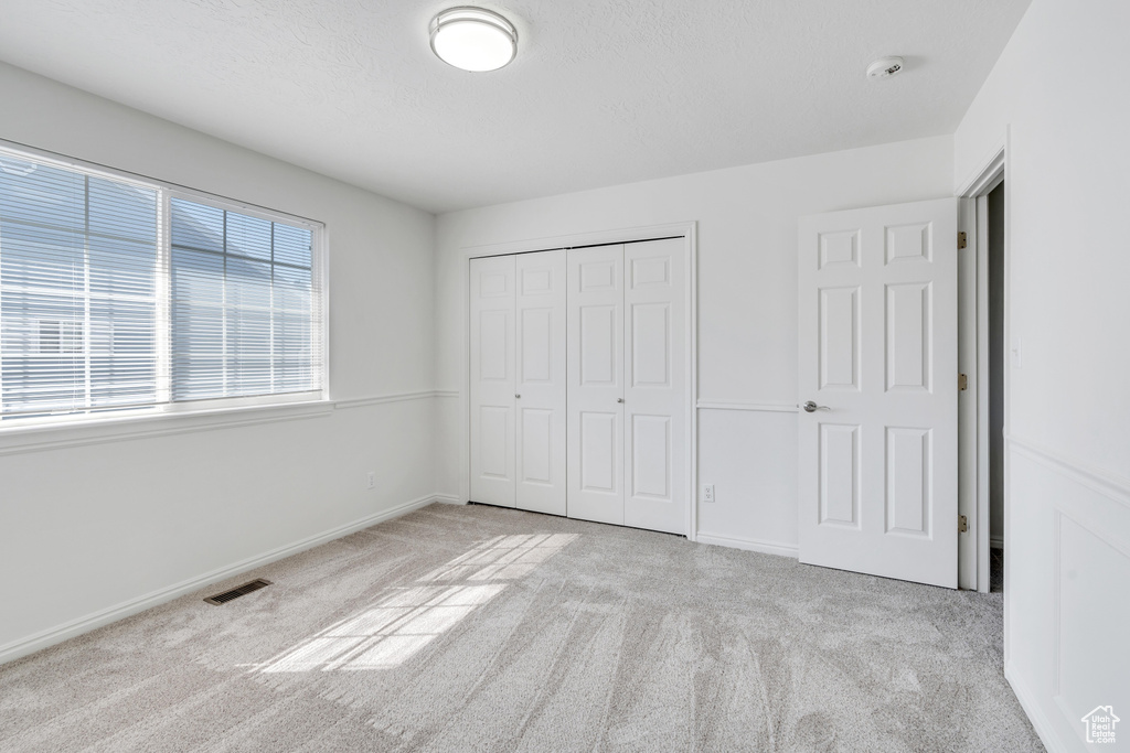 Unfurnished bedroom with light colored carpet and a closet