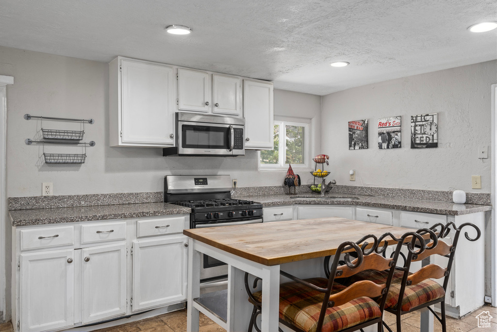 Kitchen featuring light tile patterned flooring, appliances with stainless steel finishes, and white cabinets