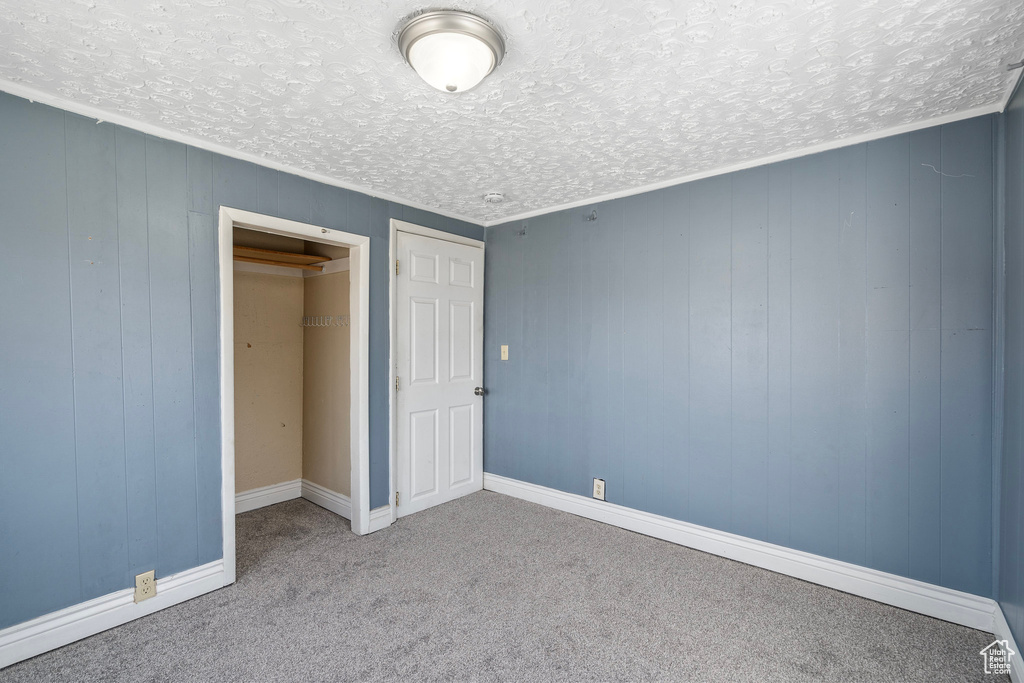 Unfurnished bedroom featuring a textured ceiling, carpet flooring, and a closet