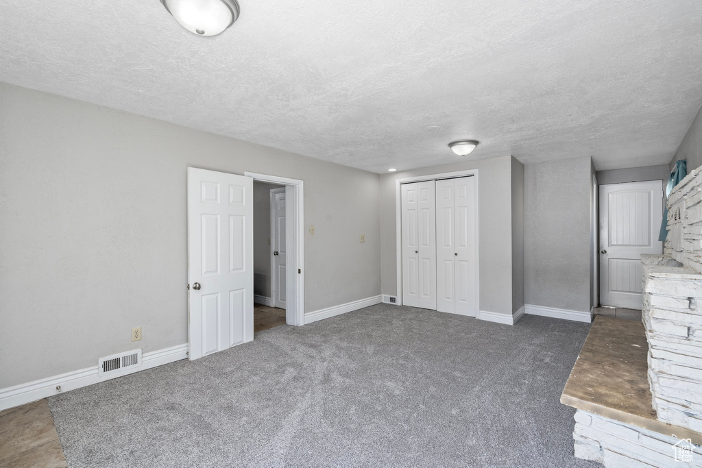 Unfurnished bedroom featuring a closet, a textured ceiling, and carpet flooring