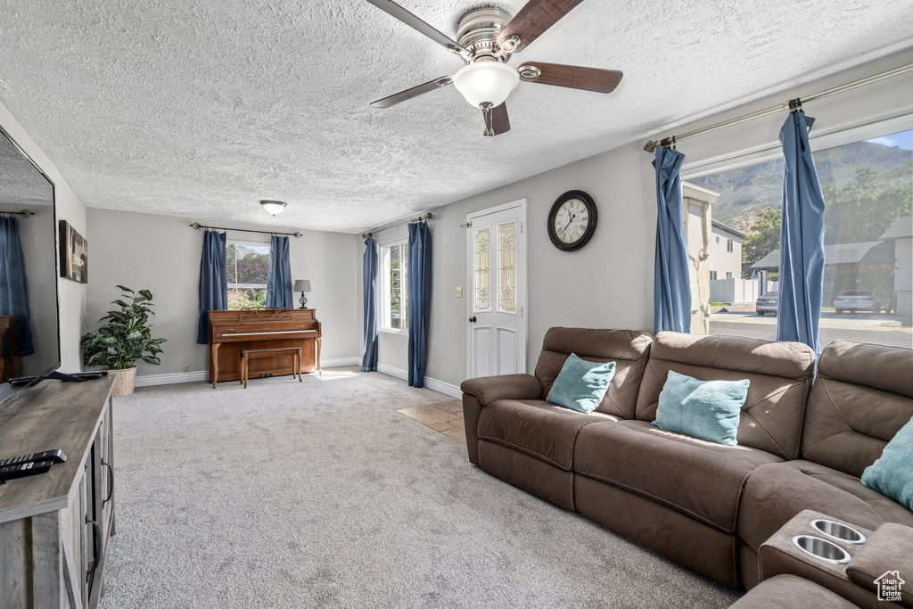 Carpeted living room featuring a textured ceiling and ceiling fan