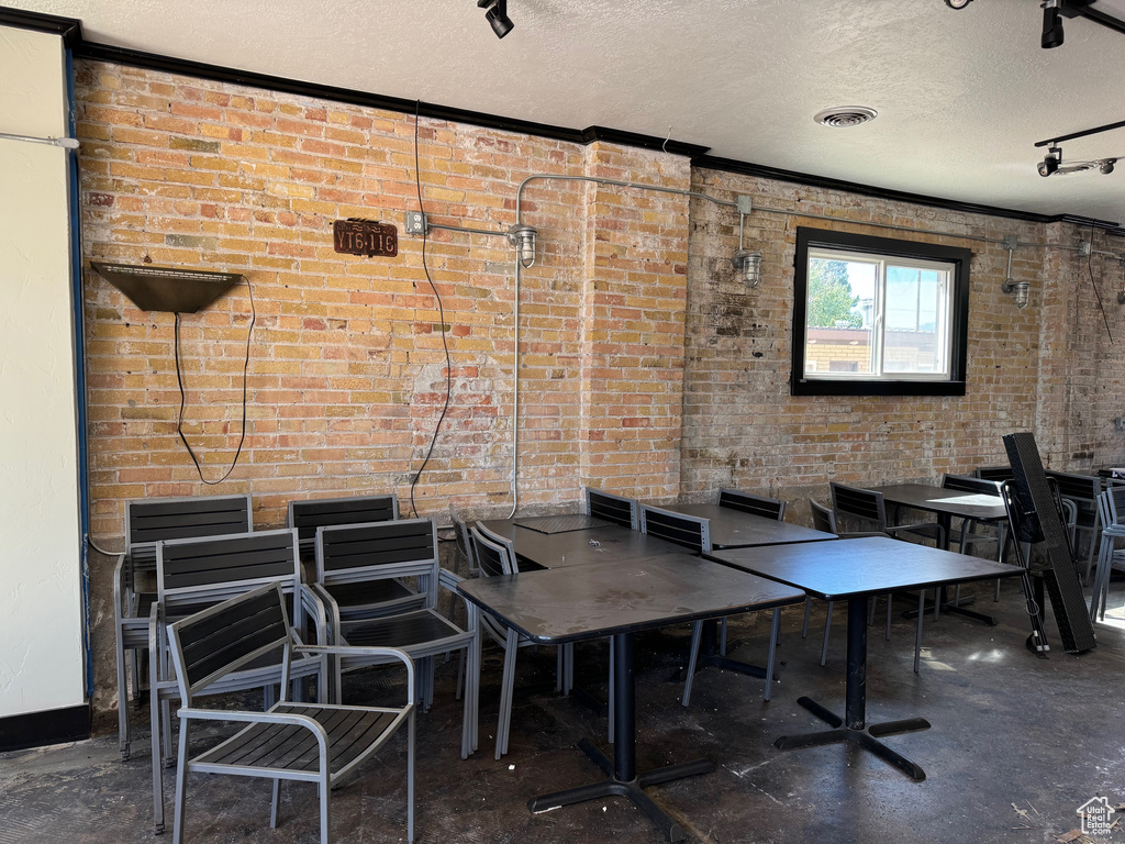 Dining room featuring a textured ceiling and brick wall