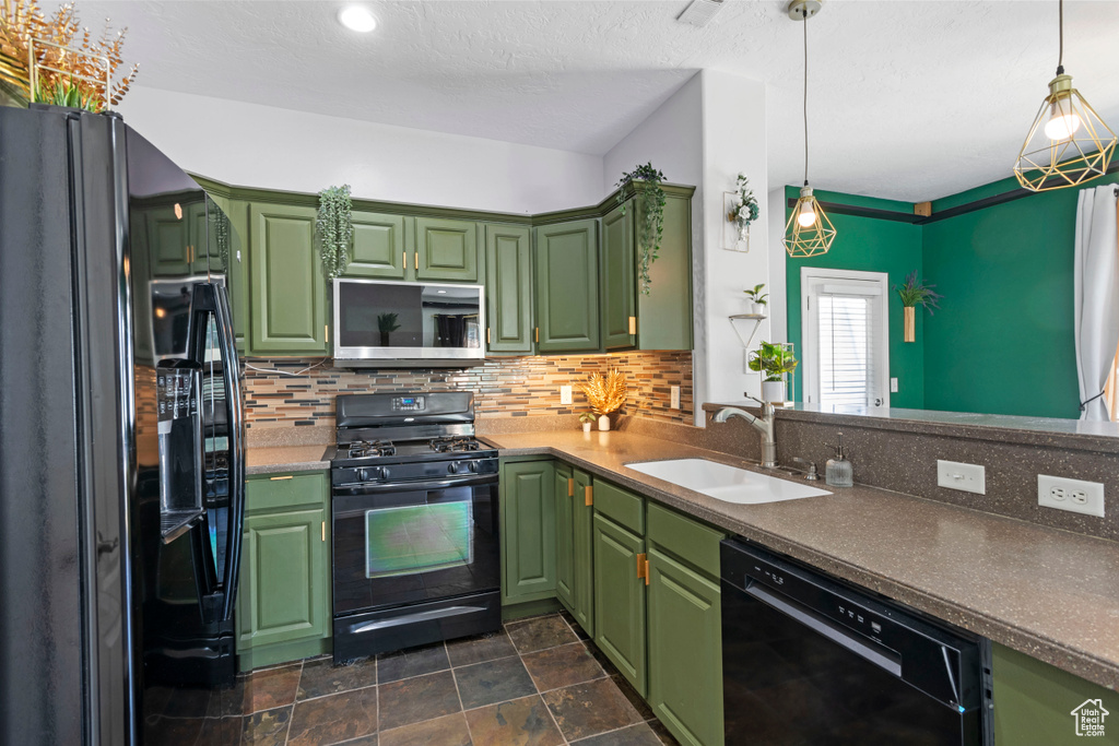 Kitchen featuring black appliances, tasteful backsplash, green cabinetry, and sink