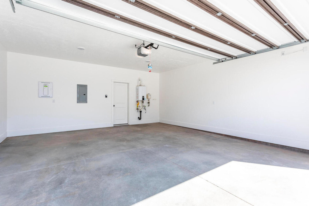 Garage with a garage door opener, water heater, and electric panel